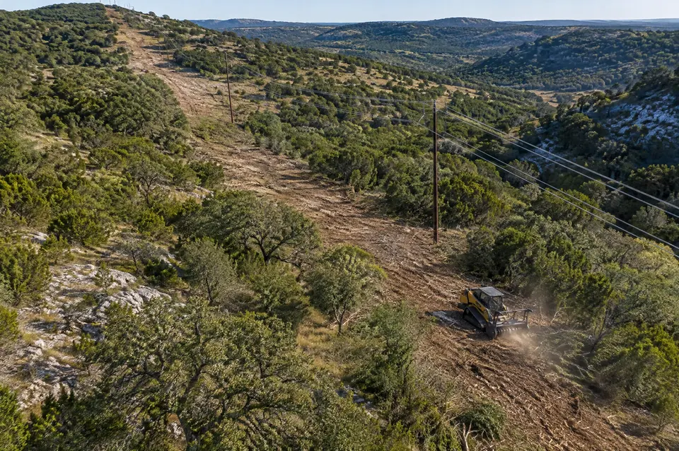 Mesquite clearing Kerrville: aerial view of a cleared corridor and power line across juniper hills in Kerr County