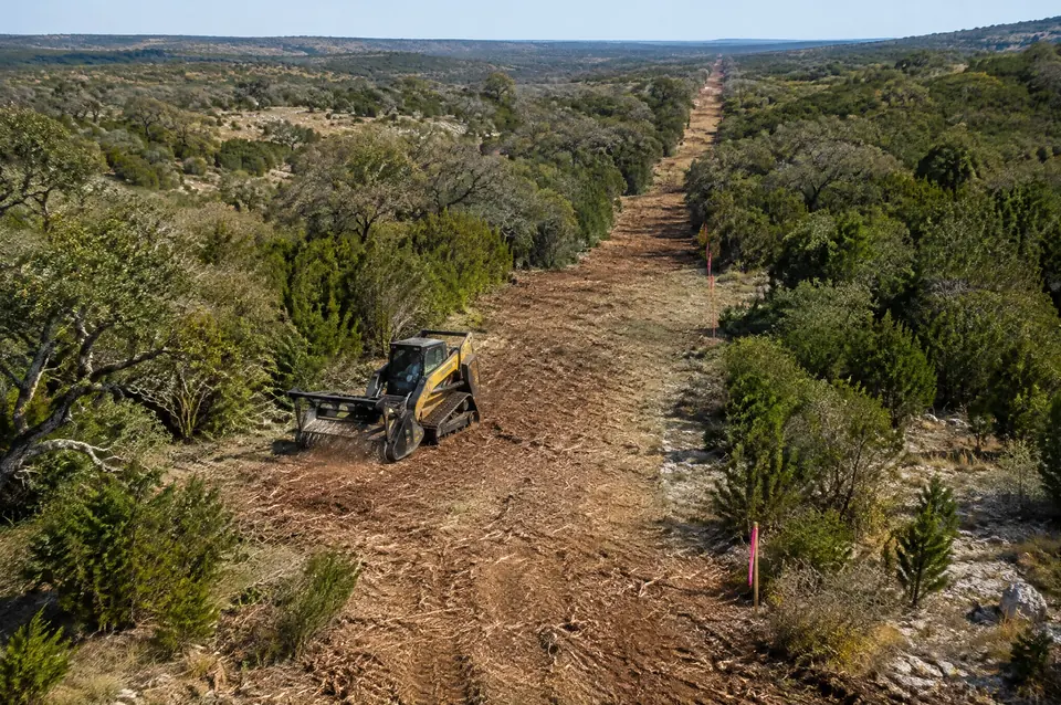 Solar site preparation: aerial view of a cleared solar project perimeter line through brush