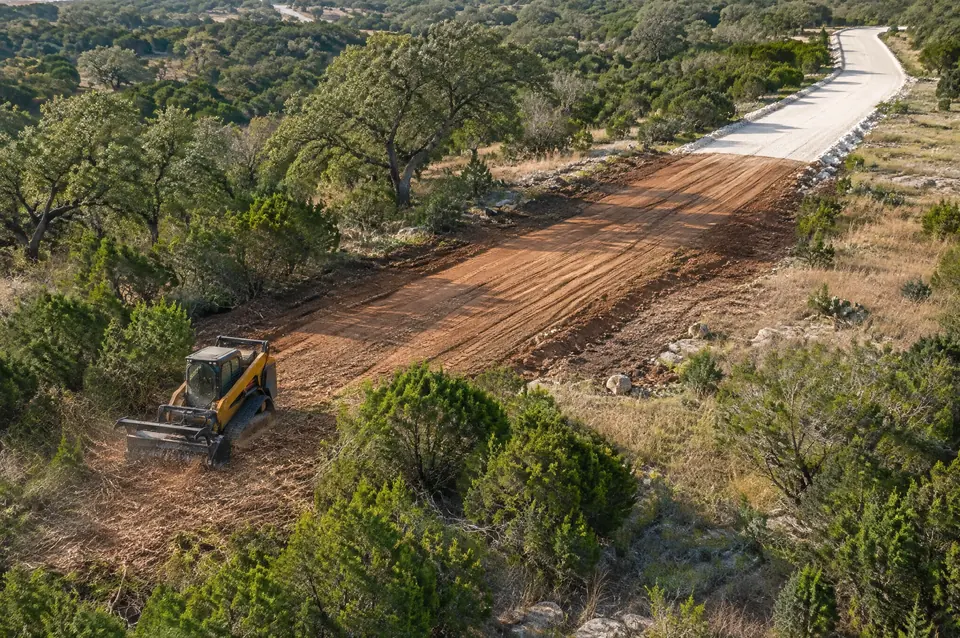 Ranch road building: aerial view of a new ranch access road going from brush to graded dirt to crushed limestone