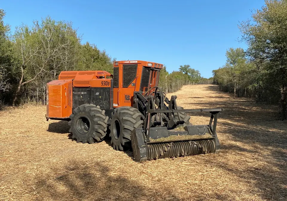 Articulated forestry mulcher beside a freshly cleared lane