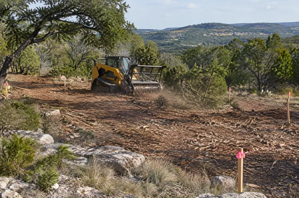Home site clearing: cleared building envelope with survey stakes on a Hill Country lot