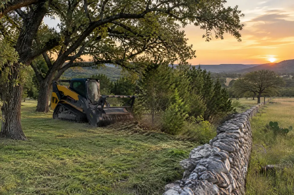 Acreage clearing Bulverde: cleared Bulverde property with mowed grass under live oaks and a dry-stack rock wall