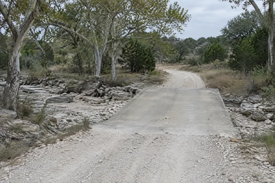 Edwards aquifer water pollution abatement plan: concrete low-water crossing over a dry rocky creek bed on a ranch road
