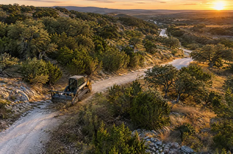 Pasture clearing Blanco TX: crushed limestone ranch road winding across Blanco County hills