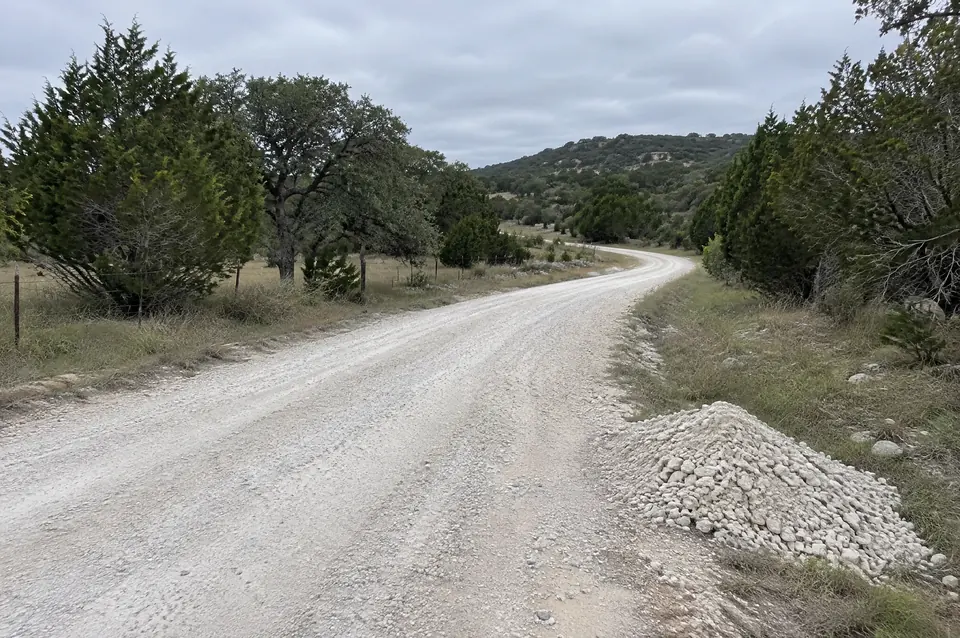 Crushed limestone road base: white crushed limestone ranch road curving through pasture and cedar