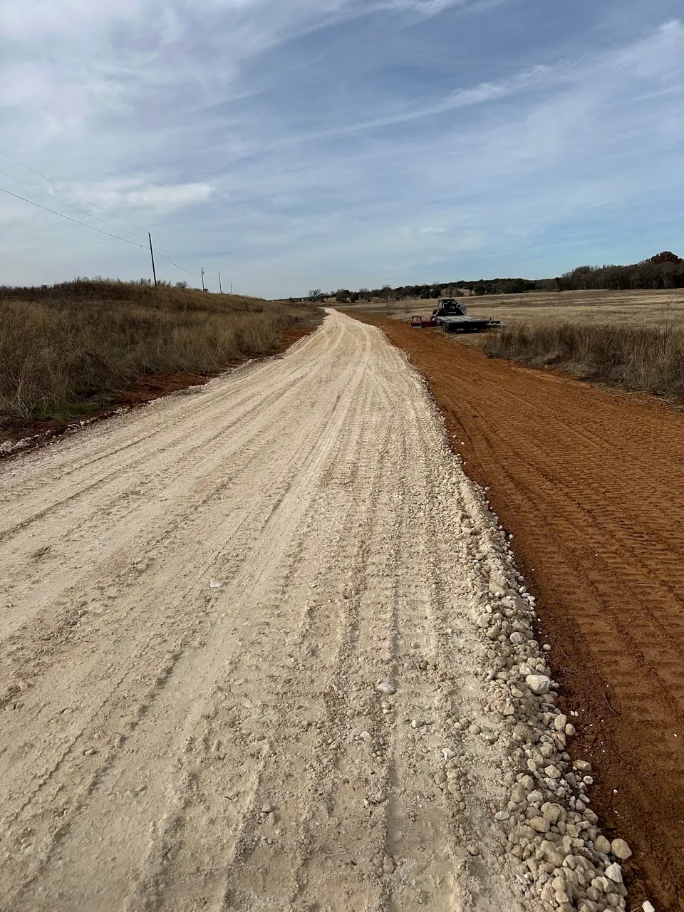 Crushed rock road with a fresh red dirt shoulder