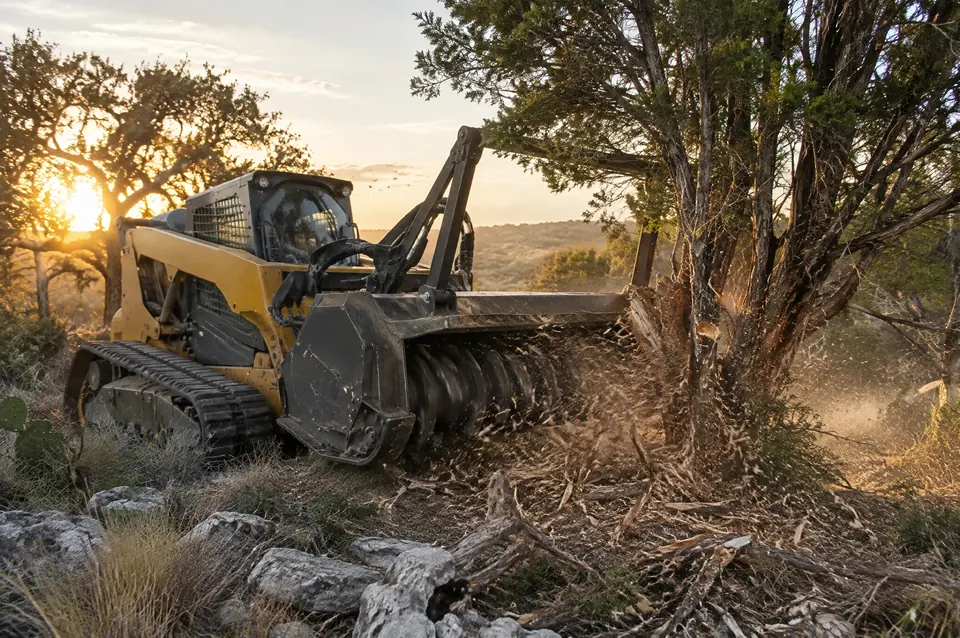 Forestry mulching services: forestry mulcher head turning a standing cedar into mulch on rocky ground