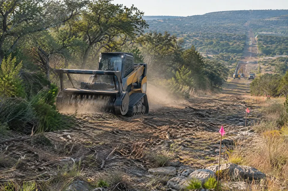 Row clearing: forestry mulcher opening a new right-of-way marked with survey flags
