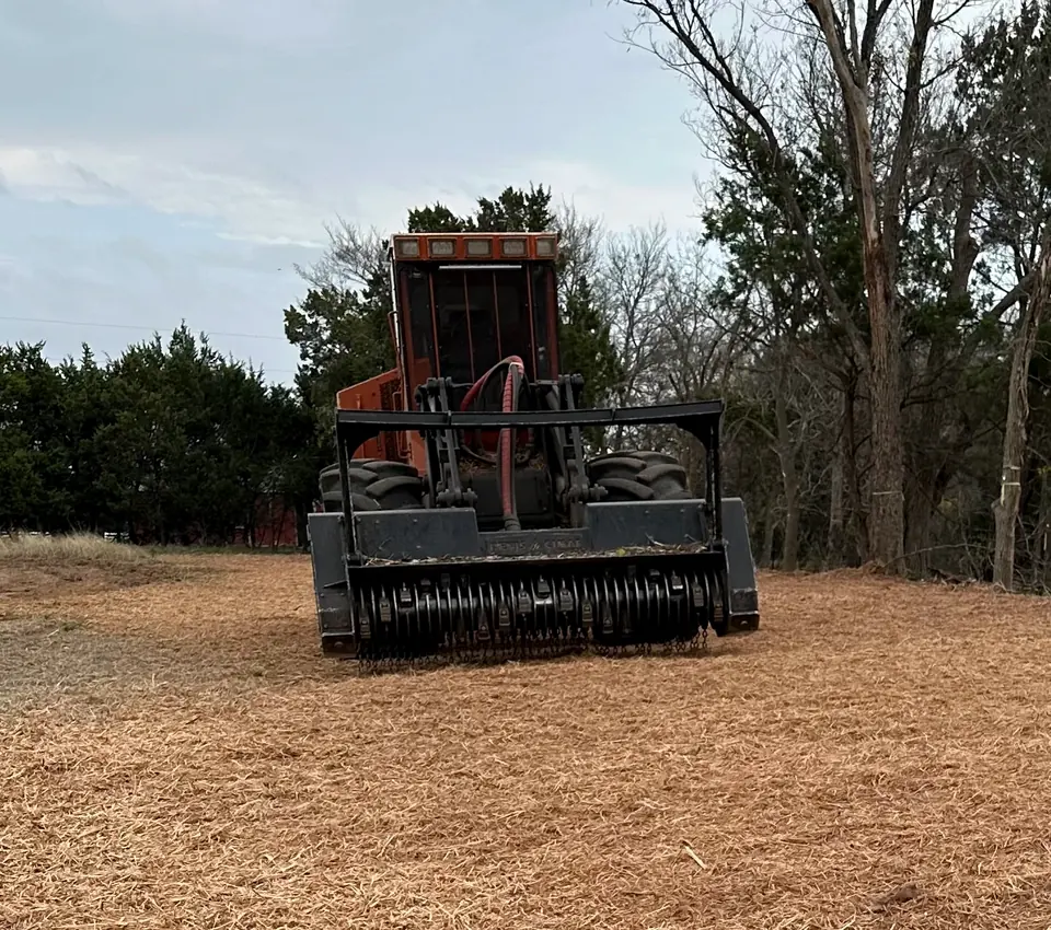 Forestry mulcher parked on fresh mulch at the edge of the woods
