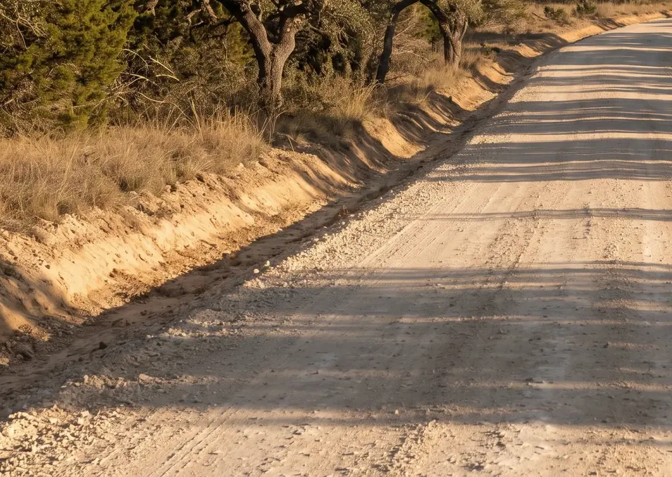 Access road building in Texas: graded road with a crowned surface and a drainage ditch along the edge