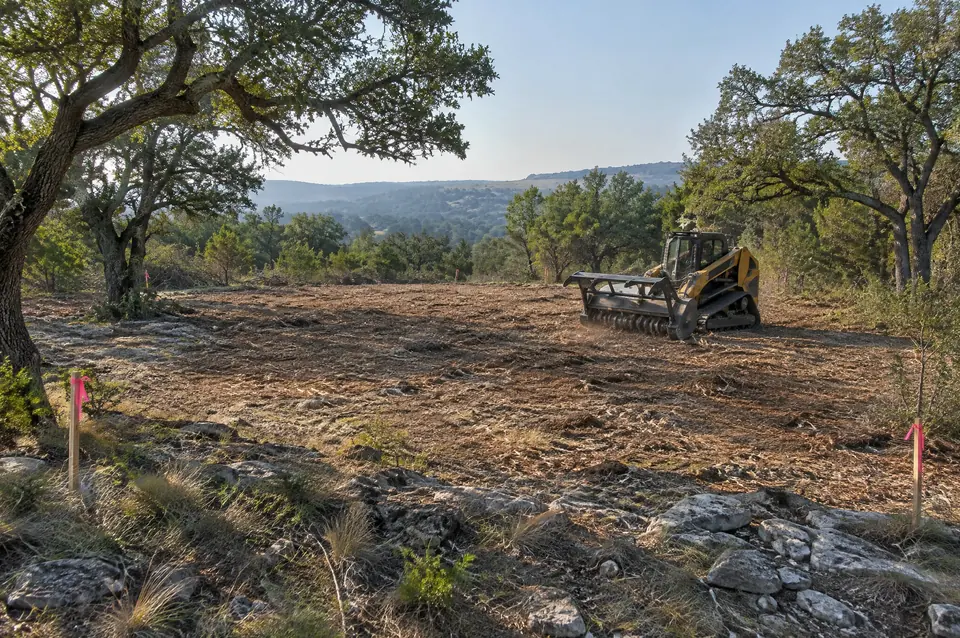 Land clearing services: Hill Country acreage lot cleared for a house with flagged corner stakes and oaks kept
