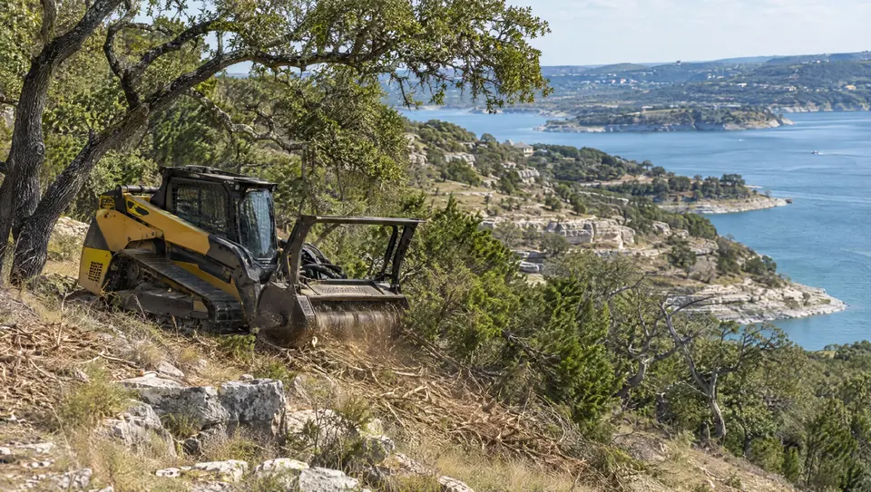Land clearing in Canyon Lake, TX: forestry mulcher on a rocky hillside lot above Canyon Lake