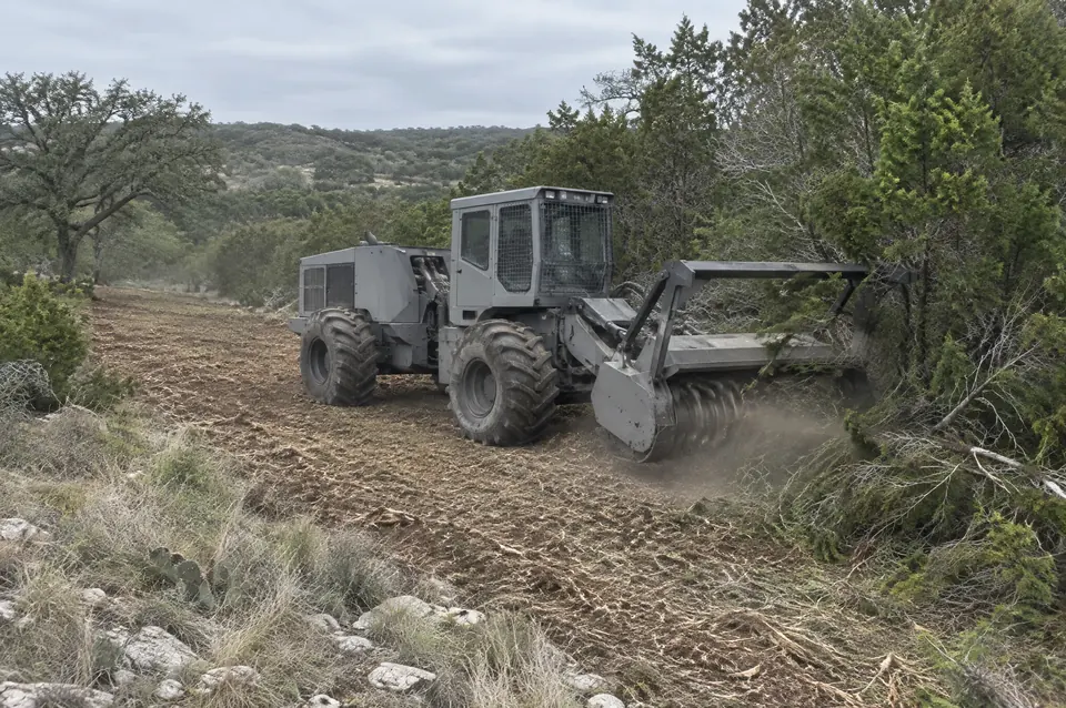 Land clearing in north Texas: articulated forestry mulcher clearing a wide swath through cedar