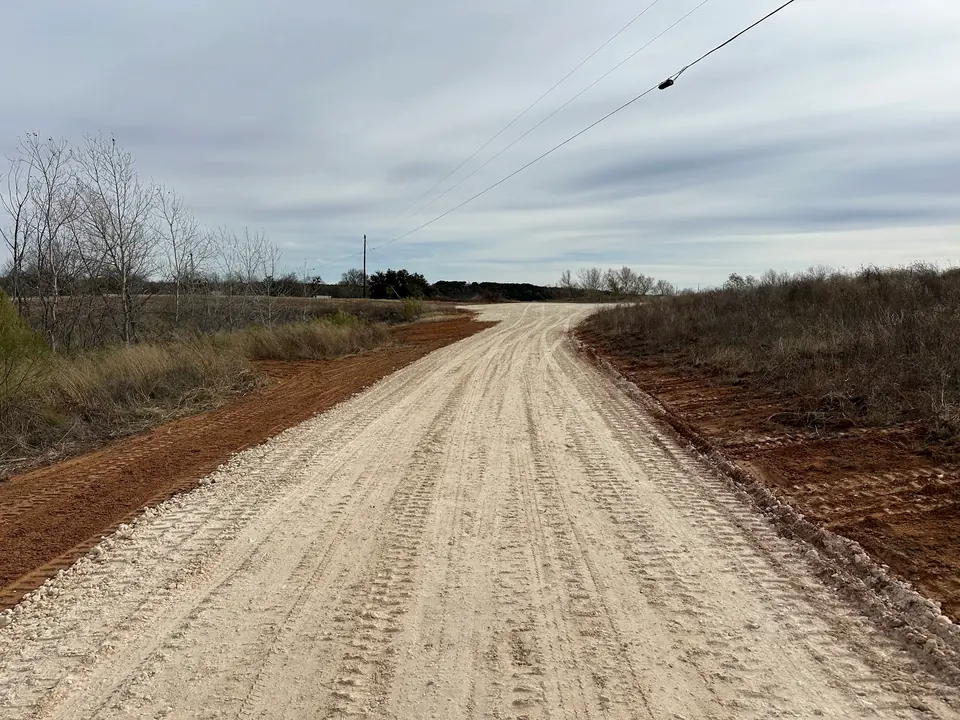 Long crushed limestone road running through ranch land