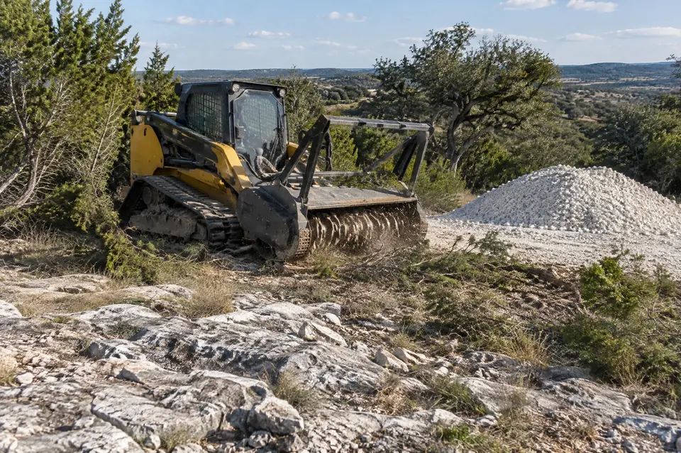 Culvert installation: loose limestone surface rock beside a pile of freshly crushed white road base