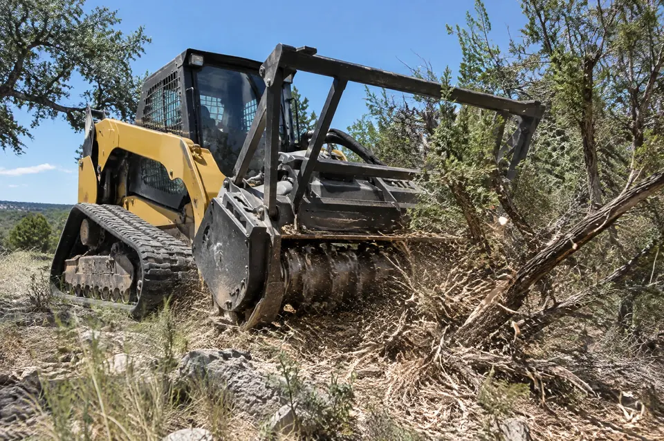 9 Arrow services: low-angle view of a yellow track mulcher grinding mesquite