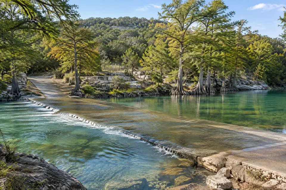 Low-water crossing on the clear Guadalupe River near Spring Branch, cypress on the banks