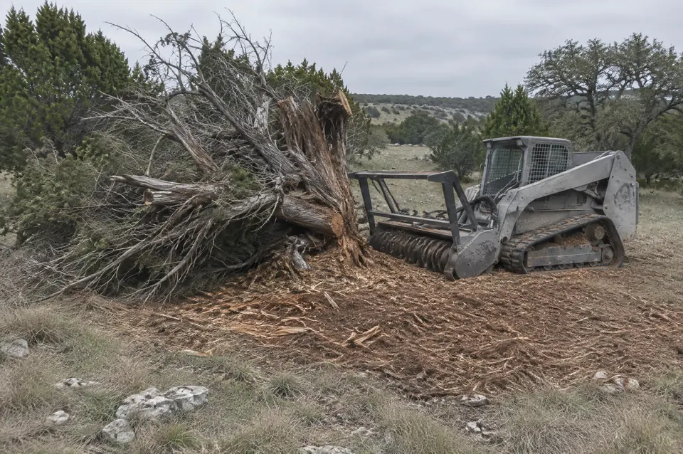 Forestry mulching north Texas: old cedar brush pile half ground down by a tracked forestry mulcher