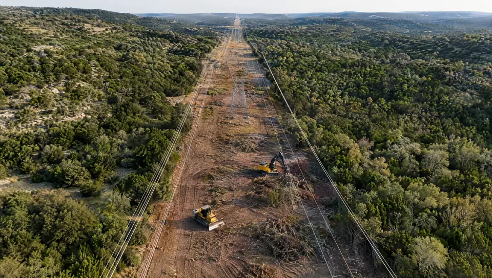 Right-of-way clearing in Texas: aerial view down a wide cleared power line right-of-way through cedar and oak hills