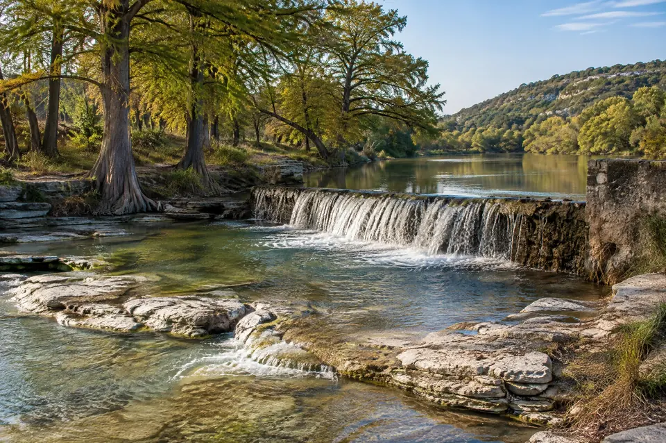 Shallow river over white limestone shelves at a low-water dam in Blanco River country