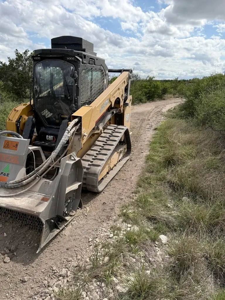 Track loader with a rock crushing head working a ranch road