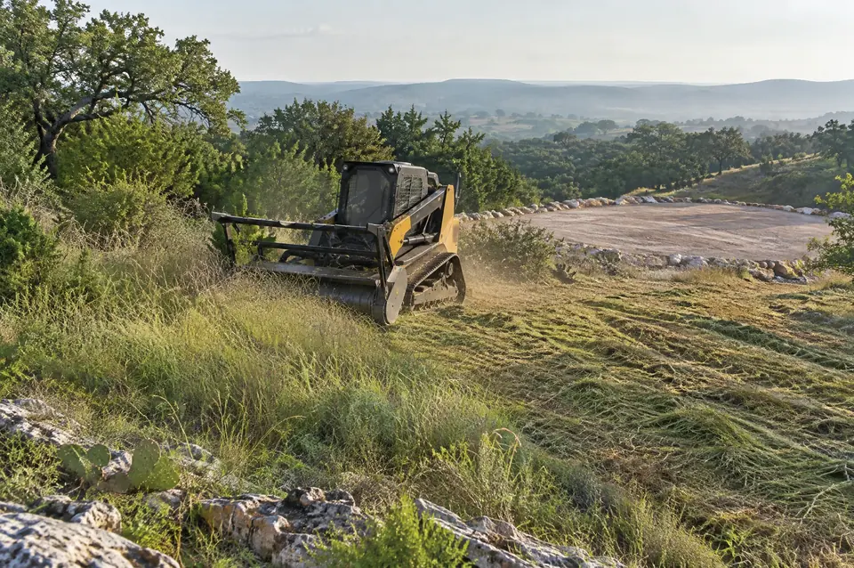 Dfw land clearing: track mulcher cutting tall grass beside a cleared pad site