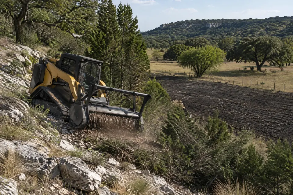 Forestry mulching near New Braunfels: track mulcher on a rocky slope above dark blackland clay near New Braunfels