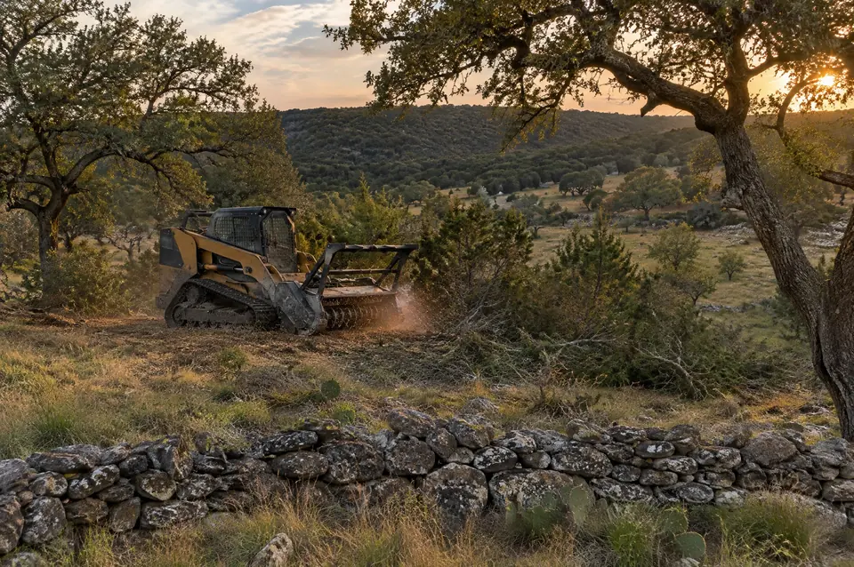 Lot clearing Spring Branch: track mulcher in Spring Branch hill pasture behind an old dry-stack rock wall